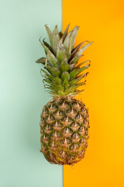 Ananas fresco su uno sfondo blu ghiaccio e arancio