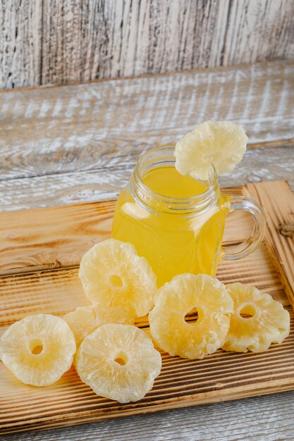 Ananas secchi in un vassoio con succo su una superficie di legno