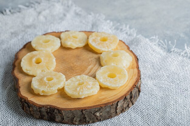 Anelli di ananas biologici essiccati posizionati su un pezzo di legno