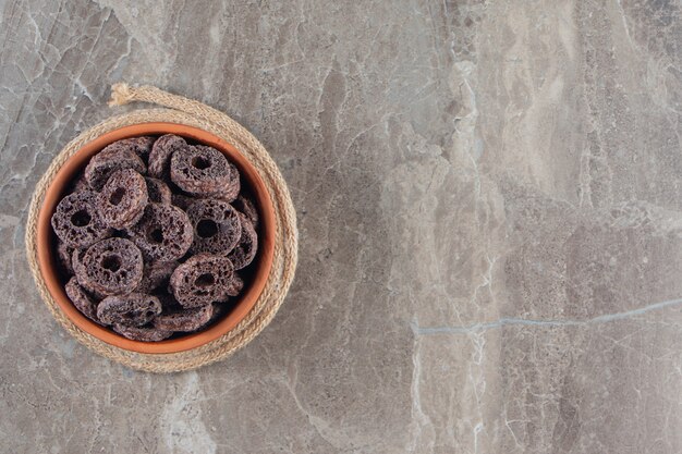 Anelli di mais al cioccolato in una ciotola sul sottopentola sul blu.