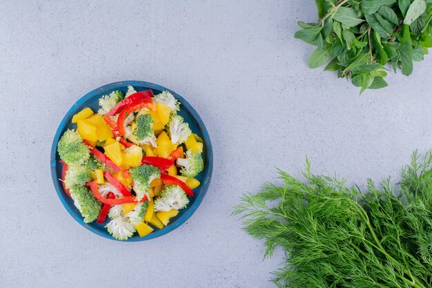 Aneto fragrante e fasci di menta accanto a un piatto di insalata su sfondo marmo. Foto di alta qualità