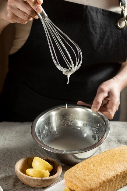 Angolo alto del pasticcere che usa la frusta per gli ingredienti della torta