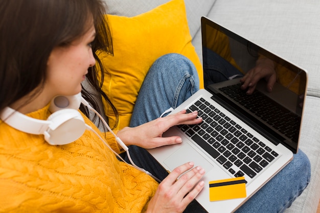 Angolo alto della donna che lavora al computer portatile con la carta di credito sulla cima