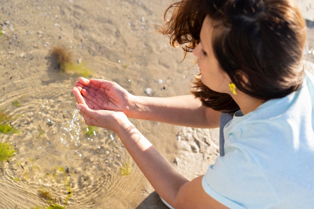 Angolo alto della donna che raggiunge per l'acqua all'aperto