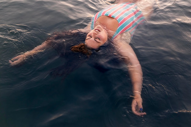 Angolo alto della donna che si rilassa nell'acqua alla spiaggia