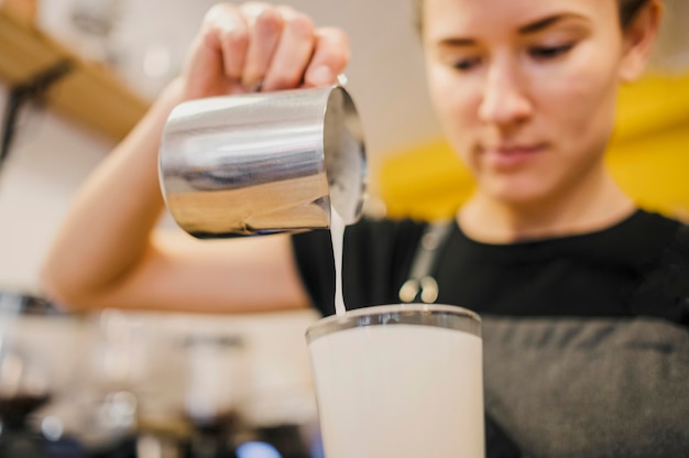 Angolo basso del barista che versa latte in vetro