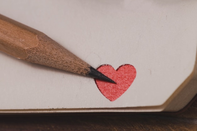 Angolo di un notebook con un cuore rosso e una matita