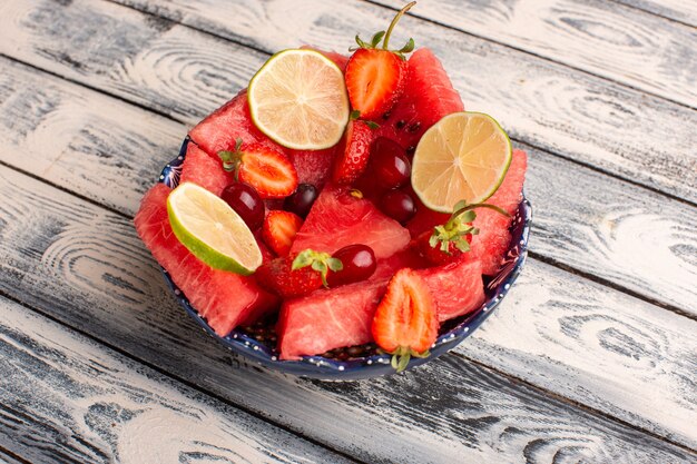 anguria a fette con fragole di limoni a fette su grigio