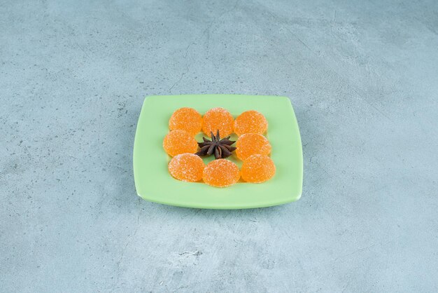 Anice circondato con marmellate su un piatto verde su marmo.