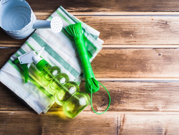 Annaffiatoio, bottiglia spray verde trasparente e corda sul tovagliolo sul tavolo