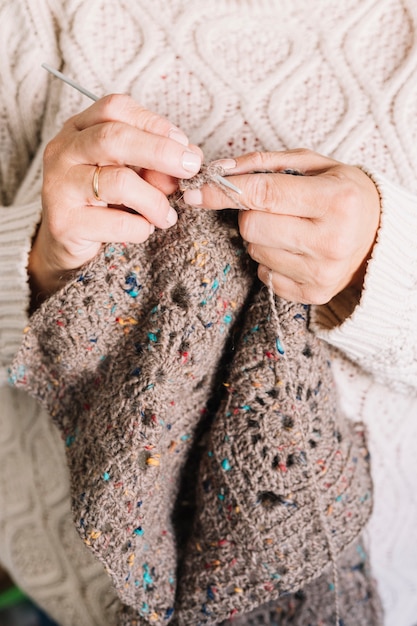 Anziana in maglione leggero che lavora a maglia sciarpa