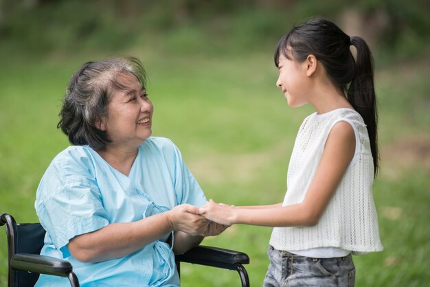 Anziana nonna in sedia a rotelle con la nipote nel giardino dell&#39;ospedale