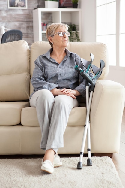 Anziana sola in pensione seduta su un divano in una casa di cura.