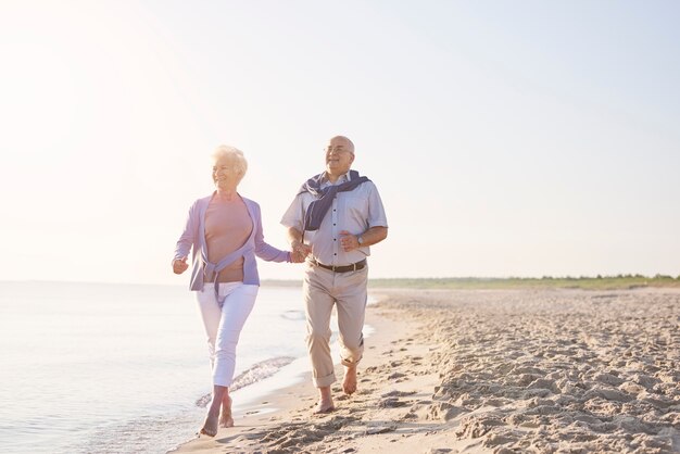 Anziani vitali sulla spiaggia. Coppia senior in spiaggia, il pensionamento e il concetto di vacanze estive