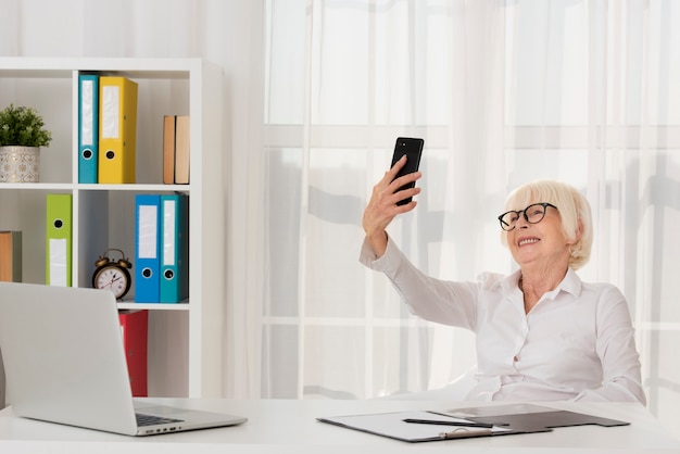 Anziano con gli occhiali che tengono il telefono