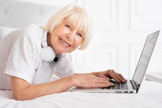 Anziano felice con le cuffie e il computer portatile