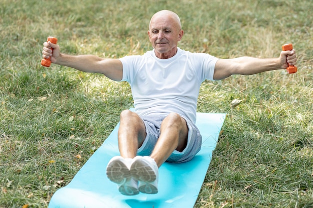 Anziano sorridente che risolve sulla stuoia di yoga