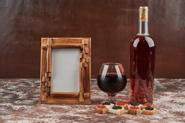 Aperitivi di pane sul marmo con caviale e vino.