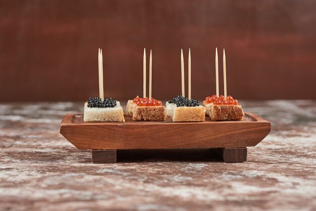 Apetizer toast con caviale su tavola di legno.