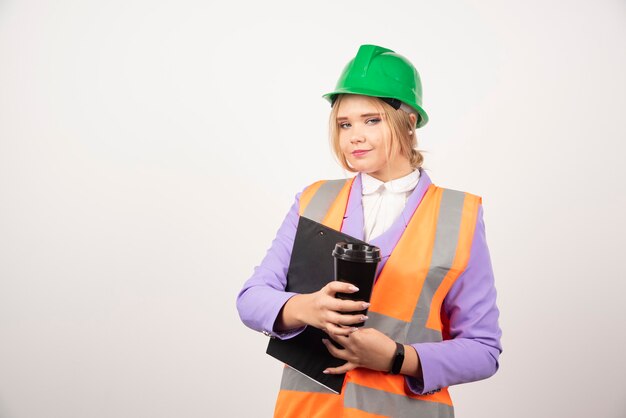 appaltatore della donna in cappello duro con appunti e tazza nera su bianco.