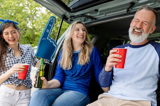 Appassionati di baseball seduti e bevendo nel bagagliaio dell'auto a una festa sul portellone