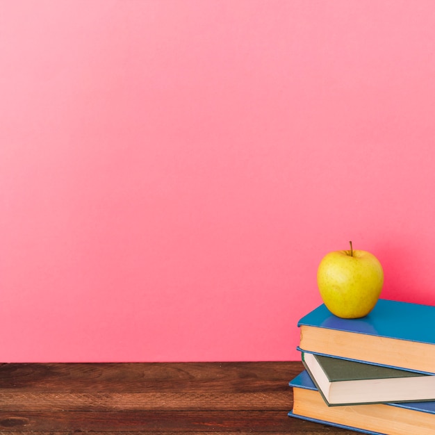 Apple e libri vicino al muro rosa