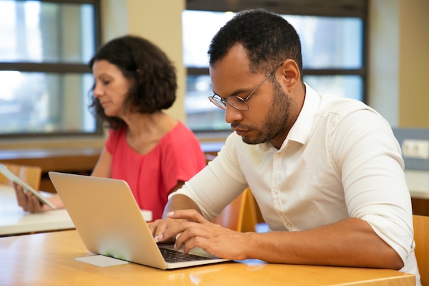 Apprendista latino maschio serio che lavora nella classe del computer