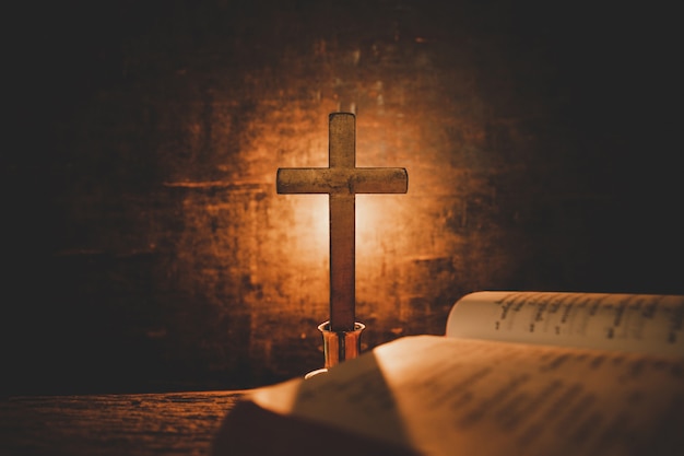 Apra la bibbia santa e la candela su una vecchia tabella di legno di quercia. Bellissimo sfondo oro Concetto di religione