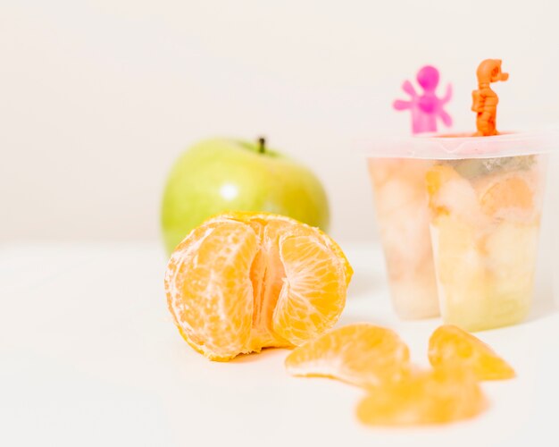 Arancia; muffa del ghiacciolo e mela sulla scrivania