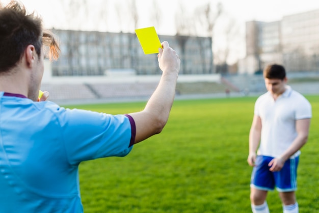 Arbitro irriconoscibile che mostra cartellino giallo