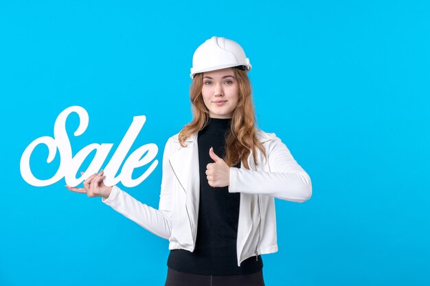 Architetto femminile di vista frontale che tiene la scrittura di vendita sul blu