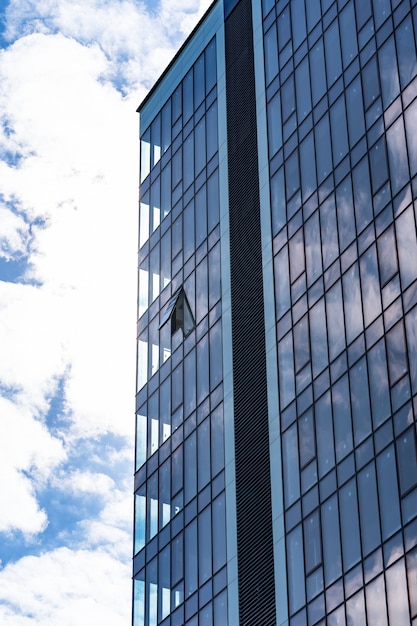 Architettura moderna della costruzione di vetro con cielo blu e nuvole