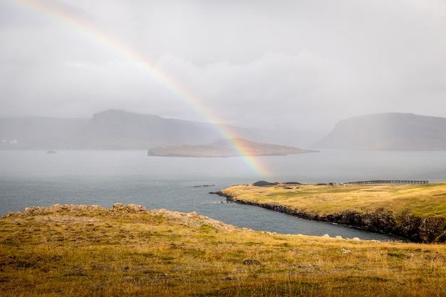 Arcobaleno sul lago con le sagome delle scogliere in Islanda