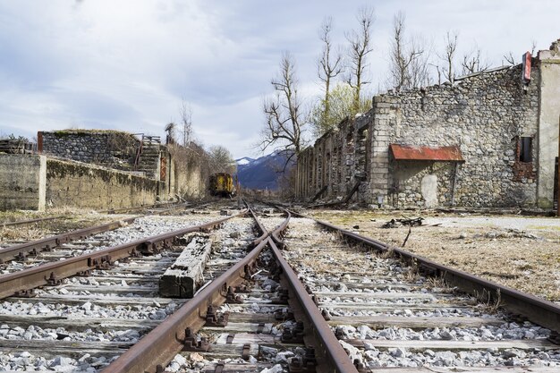 Area con binari del treno circondata da vecchi edifici in cemento sotto un cielo nuvoloso