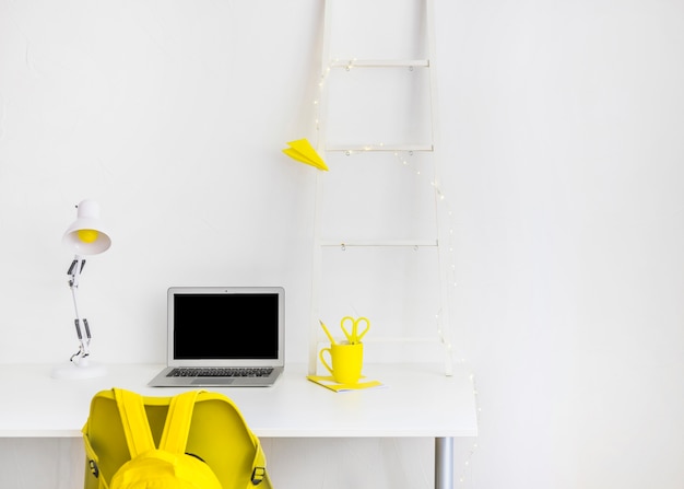 Area di lavoro creativa nei colori bianco e giallo con laptop
