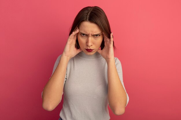 Arrabbiato donna abbastanza caucasica mani sulle tempie in rosa