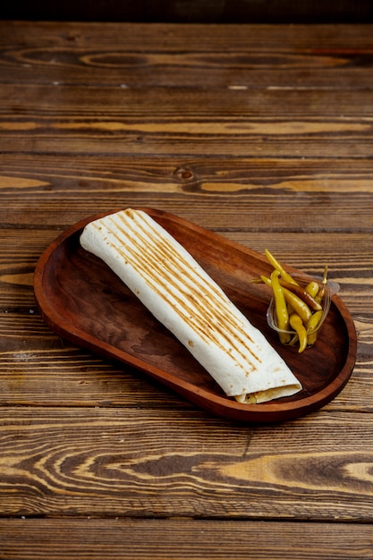 Arrotoli il pane e il peperoncino della pita su un vassoio di legno