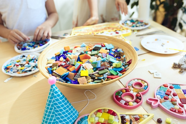 arte puzzle mosaico per bambini, gioco creativo per bambini. le mani stanno giocando a mosaico al tavolo. I dettagli multicolori variopinti si chiudono su.