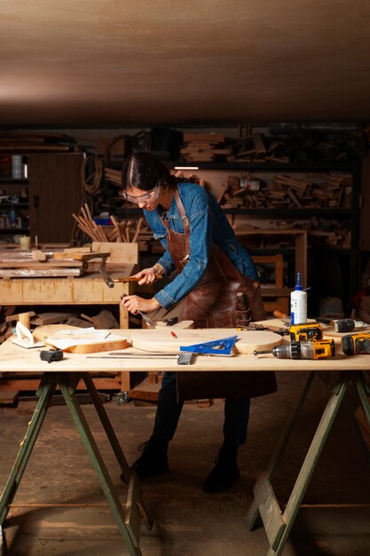 Artigiano a figura intera che fa il taglio del legno