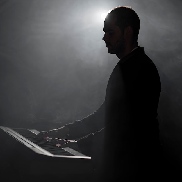 Artista che suona effetti di fumo e ombre al pianoforte