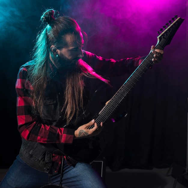 Artista che suona la chitarra e guarda lo strumento