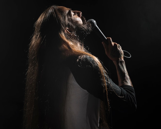 Artista con i capelli lunghi che tiene un microfono sul palco