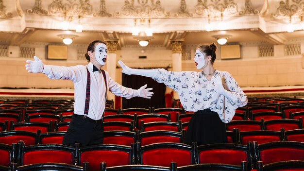 Artista di mimo maschio e femmina in piedi tra la sedia che prova in auditorium