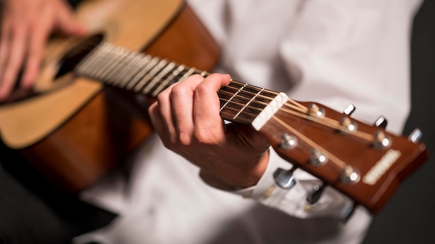 Artista in camicia bianca che gioca il primo piano della chitarra
