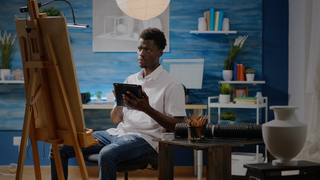 Artista uomo di colore con tavoletta digitale in studio officina