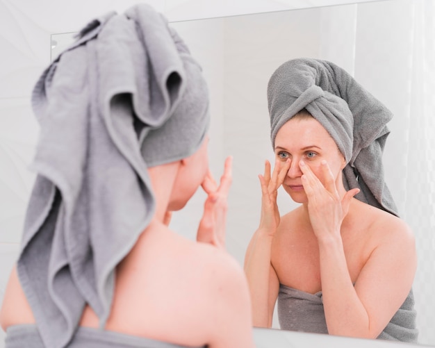 Asciugamani d'uso della donna che si guardano allo specchio