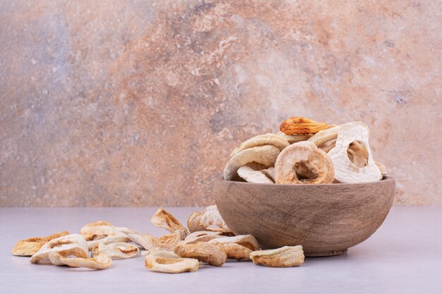 Asciugare le fette di mela in una tazza di legno su grigio.