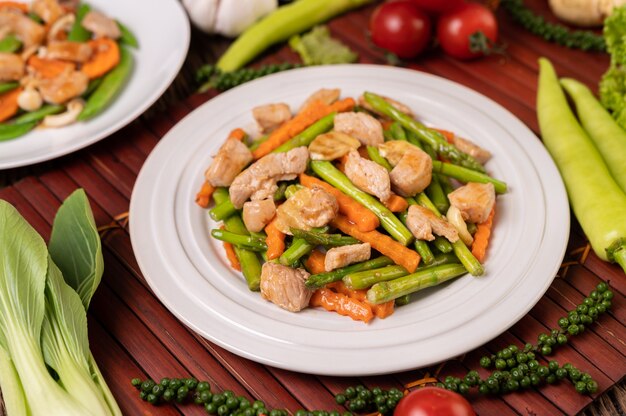 Asparagi e carote saltati in padella con carne di maiale in un piatto bianco