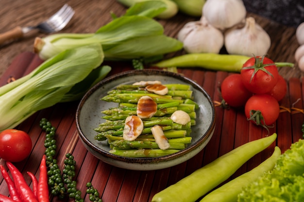 Asparagi fritti con salsa di ostriche in un piatto con peperoni