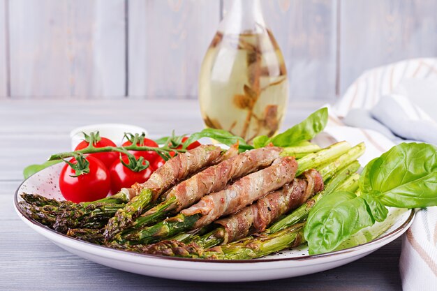 Asparagi verdi alla griglia avvolti con pancetta sul tavolo di legno.